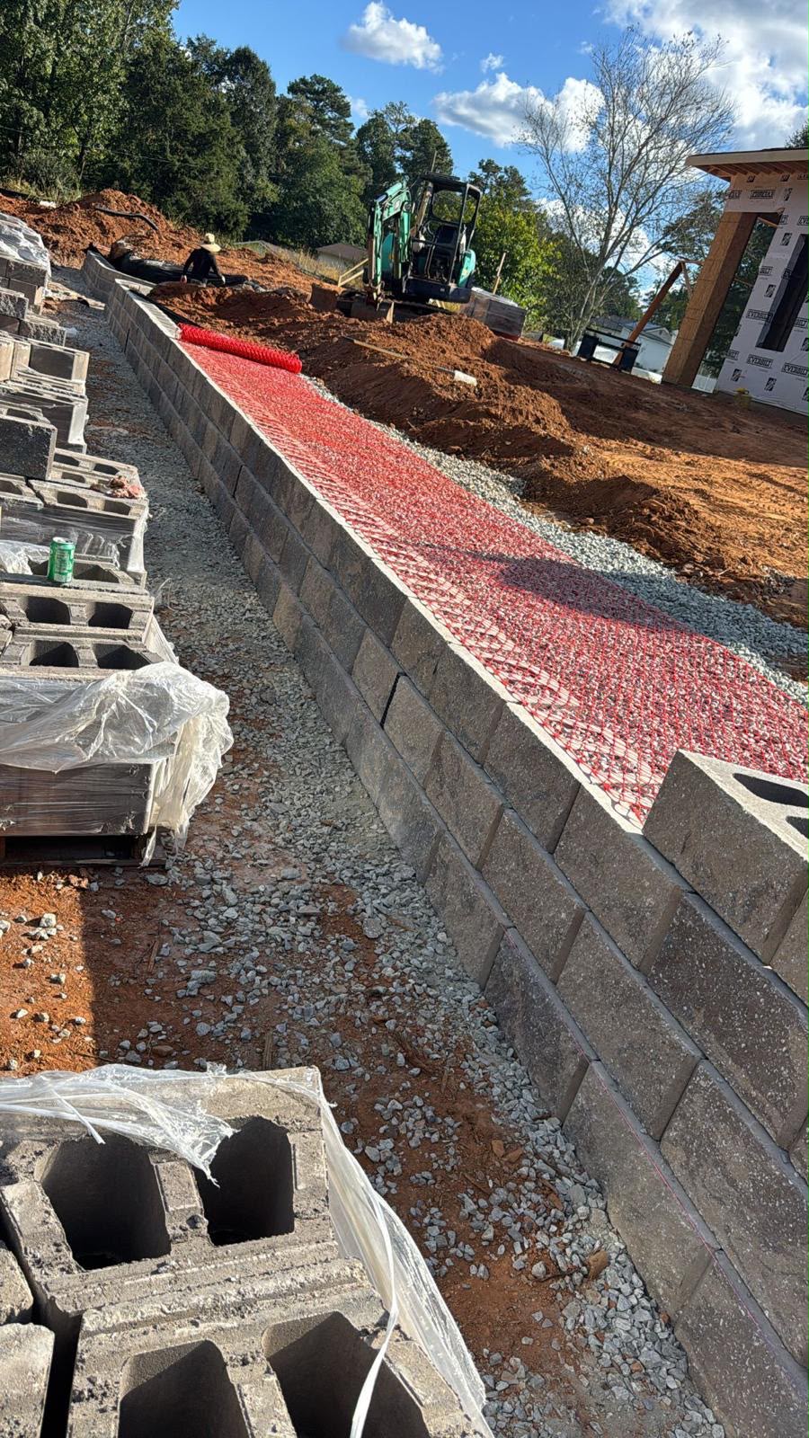 Retaining wall under construction with drainage stone and geogrid