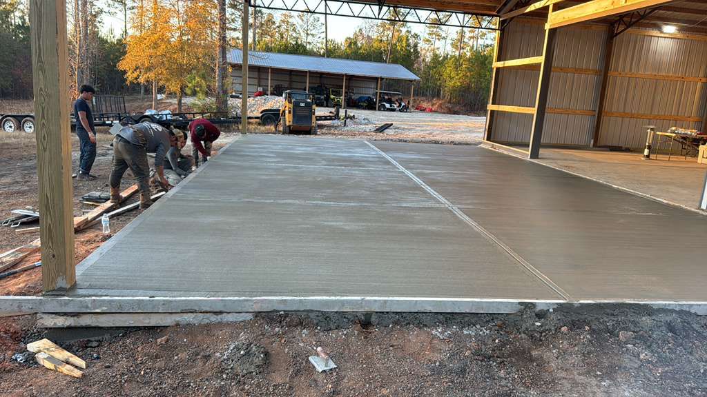 Crew finishing a freshly poured pavilion slab at sunset