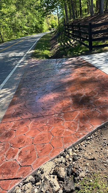 Red-tinted stamped concrete driveway with stone pattern
